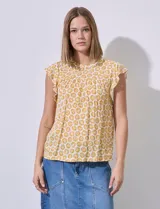 Blusa estampada color amarillo con flores blancas, de corte recto y mangas cortas con volados. Presenta frunces en la parte delantera y abertura con botón en la espalda. Marca Premise.