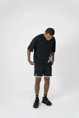 Short deportivo negro con ribete blanco, corte holgado, cintura elástica y logo estampado en la pierna izquierda.