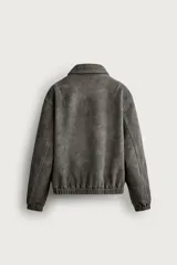 Cazadora de hombre regular fit confeccionada en tejido efecto ante, con acabado lavado, cuello solapa, manga larga, bolsillos de plastrón con solapa en la cadera, detalles elásticos en puños y cintura, y cierre frontal de cremallera.