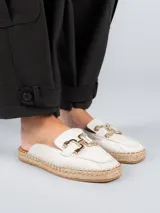 Alpargatas tipo mule color blanco, confeccionadas en cuero, con detalle de herraje metálico dorado en el empeine y suela de yute trenzado.