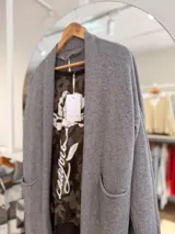Saco largo abierto de tejido de punto, color gris, con bolsillos delanteros y puños acanalados.