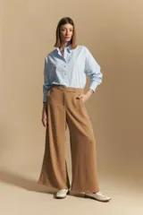 Pantalón ancho color tostado, de silueta fluida y cintura elastizada. Presenta una pretina ancha con botones metalizados irregulares.
