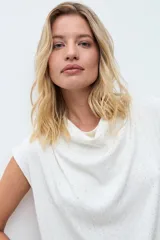 Blusa negra con pequeños puntos brillantes, cuello drapeado y mangas cortas.