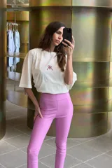 Pantalón largo de ecocuero color lila, con tiro alto, calce ajustado y botamanga irregular.