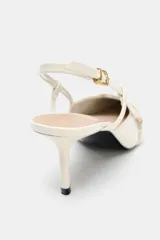 Zapato de tacón color blanco hueso, con punta fina, tiras finas con hebillas doradas y tira trasera ajustable con hebilla. Tacón fino.