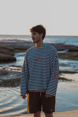 Buzo reversible de manga larga con estampado de rayas horizontales blancas y azul marino en un lado, y liso azul marino en el otro. Presenta cuello redondo y un corte holgado.