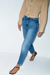 Jeans de tiro alto con corte mom fit, diseño de cinco bolsillos y raya planchada frontal. Presenta cierre frontal con cremallera y botón.