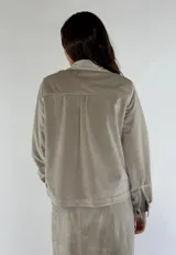 Chaqueta azul marino de terciopelo con cuello camisero, cierre frontal con botones, dos bolsillos de parche con solapa y mangas largas con puños abotonados.