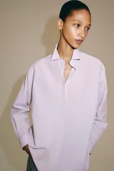 Camisa de manga larga confeccionada en hilatura con mezcla de algodón, con cuello solapa, bajo redondeado y cierre frontal oculto con botones.