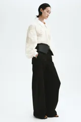 Blusa oversized de tejido transparente color crudo, con detalles bordados en relieve, cuello camisero, cierre frontal de botones y mangas largas abullonadas con puños ajustados.