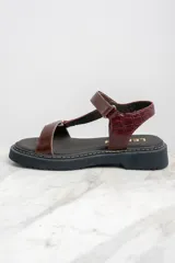 Sandalias de cuero color marrón con textura tipo cocodrilo, plataforma plana y tira ajustable con hebilla.