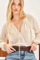 Camisa de manga larga confeccionada en tela plumeti, con cuello redondo, tajo delantero con cordones ajustables y volados verticales en el frente.