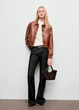 Jeans de tiro medio con diseño flare y lavado oscuro, confeccionados en tejido de algodón estilo tejano vaquero. Cuentan con cinco bolsillos, trabillas para cinturón y cierre frontal con botón y cremallera.
