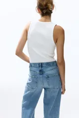 Jean tobillero barrel de tiro alto, confeccionado en denim de algodón rígido color celeste con efecto deslavado. Presenta diseño curvo en las piernas con volumen y tiras finas para atar en los bajos.