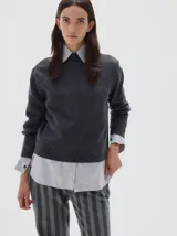 Polera de punto en color celeste, con cuello alto y manga larga. Presenta un pequeño logo bordado en el centro del pecho y terminaciones en tejido acanalado.