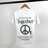 Remera blanca de algodón con cuello redondo y estampado en la espalda con la frase "We've Got To Come Together", un símbolo de la paz y un texto en letra pequeña.