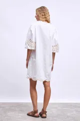 Vestido blanco de lino con escote en V, mangas cortas abullonadas y bordados florales en beige en mangas y ruedo.