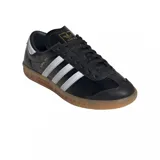 Championes adidas modelo Hamburg, de diseño clásico con exterior de cuero negro, las icónicas tres tiras laterales en blanco y suela de goma color caramelo. Incluye el nombre del modelo en letras doradas en el lateral.