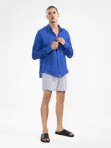 Short de baño blanco con estampado de lunares en tonos azul y naranja. Cuenta con cintura elástica con cordón regulable, bolsillos laterales y trasero con cierre, y suspensor de malla fina hipoalergénico.