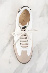 Zapatillas deportivas de cuero blanco con puntera y talón en gamuza color beige. Detalle de pelo animal print en el talón y suela de goma color caramelo.