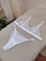 Conjunto de lencería compuesto por un bralette triangular de encaje con breteles regulables y una tanga colaless regulable con detalle de encaje.