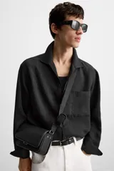 Bandolera negra con acabado grabado, compartimento principal con cierre de solapa imantada, bolsillo interno con cierre y bolsillo frontal con cierre. Incluye asa de hombro ajustable y monedero.