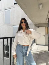 Camisa cruzada de color blanco, manga larga con puños amplios y lazo para atar en la cintura.