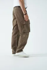 Pantalón cargo de canvas color marrón, con tiro medio, múltiples bolsillos laterales y traseros, y cierre frontal con botón y cremallera.