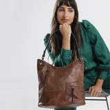 Cartera tipo hobo de cuero sintético color marrón con textura grabada. Cuenta con dos bolsillos frontales con cierre metálico, apertura superior con cierre, correa corta para el hombro y correa larga desmontable y regulable.