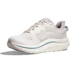 Championes Hoka modelo Kawana 2, color gris claro con detalles en azul y blanco. Presenta una suela con diseño moteado y logo de la marca en el lateral.
