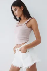 Musculosa corta de ajuste entallado en punto acanalado, color rosado pálido. Presenta escote cuadrado con un ribete de volado fruncido que se extiende sobre los breteles.