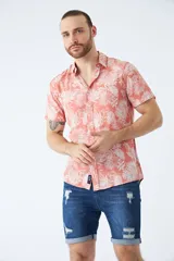 Camisa de manga corta con estampado botánico de hojas en tonos azul y blanco. Presenta cuello clásico, cierre frontal abotonado y corte slim.