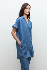 Túnica corta de lyocell color azul jean, con cuello en V, cuello camisero sutil, mangas cortas y costuras con pespuntes visibles en el frente.