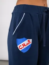Pantalón de piqué recto color azul marino, con cintura elástica y cordón ajustable. Presenta el escudo del Club Nacional de Football en el muslo izquierdo y el logo de Umbro en el muslo derecho.