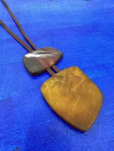 Collar de largo regulable con cordón de cuero y dos piezas colgantes de resina en tonos tierra y marmolados.