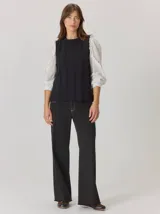 Chaleco de paño con diseño bicolor, frente en color negro y espalda en color marrón con textura de espiga. Presenta un maxi bordado de hoja en la parte posterior y detalles de tejido en los bordes.