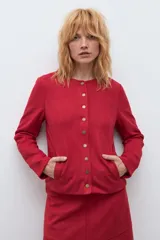 Chaqueta de textura simil gamuza en color rojo, con cuello redondo, cierre frontal mediante botones metálicos y bolsillos laterales.