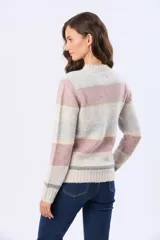 Buzo de tejido de punto con diseño de rayas horizontales en tonos neutros, beige y detalles en rosa y gris. Presenta cuello redondo, mangas largas y terminaciones en rib acanalado en puños y ruedo. Incluye una pequeña etiqueta de cuero sintético en el lateral inferior.