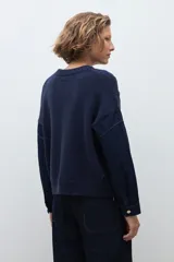 Sweater de punto trenzado en color azul marino, con cuello redondo y mangas largas. Presenta un diseño de tejido con textura en el frente y mangas lisas.
