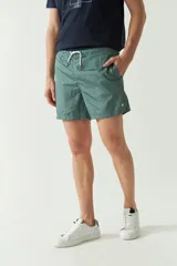 Short de baño estampado con diseño geométrico en tonos verdes, cintura elástica con cordón ajustable, bolsillos laterales y bolsillo trasero.