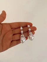 Caravanas colgantes de metal plateado con diseño de perlas de distintos tamaños, incluyendo perlas barrocas en la parte inferior.