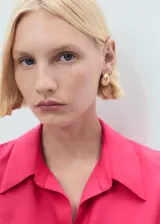 Camisa sin mangas de lyocell color fucsia, con cuello camisero y cierre frontal de botones.