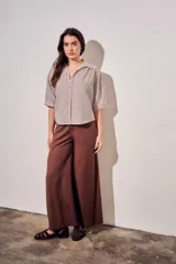 Camisa de corte oversize con estampado de rayas verticales en tonos marrón y beige. Presenta cuello camisero, cierre frontal con botones y mangas cortas con caída relajada.