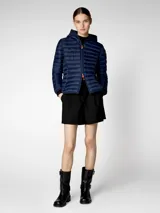 Campera puffer azul marino con capucha, cierre frontal con cremallera naranja, bolsillos laterales ocultos y puños y dobladillo elásticos de Lycra. Tiene parche de logo en goma en la manga y tiradores de cremallera en color naranja.