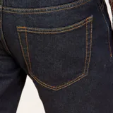 Pantalón de jean de corte recto, color azul oscuro, con bolsillos delanteros y traseros, y terminación con dobladillo.