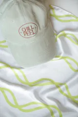 Pañuelo de seda blanco con estampado de líneas curvas en color verde lima, y texto sutil en la tela.