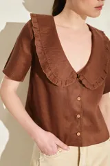 Blusa de lino color rojo, con mangas cortas, cuello en V con solapa redonda fruncida y cierre frontal de botones.