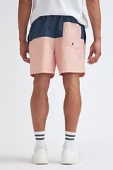 Short de baño con diseño de bloques de color, presentando una franja superior en azul marino y el resto de la prenda en color rosa. Cuenta con cintura elástica con cordón ajustable.