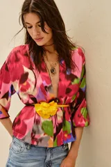 Kimono de corte holgado con estampado floral abstracto en tonos fucsia, rosa, verde y azul. Presenta mangas tres cuartos y diseño abierto frontal.