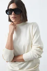 Polera de tejido de punto con cuello alto y diseño de rayas verticales sutiles. Presenta un ajuste al cuerpo y mangas largas.
